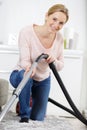 Happy young woman hoovering carpet at home