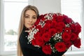 Happy young woman with a huge bouquet of red roses. Flowers for any holiday. Sending flowers to loved. Flowers as a Royalty Free Stock Photo