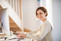 A happy young woman indoors, working in a home office. Royalty Free Stock Photo