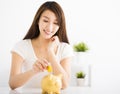 Happy young woman Inserting Coin In Piggy bank