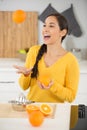 happy young woman joggling with oranges in kitchen Royalty Free Stock Photo