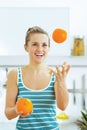 Happy young woman joggling with oranges in kitchen Royalty Free Stock Photo