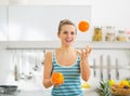 Happy young woman joggling with oranges in kitchen Royalty Free Stock Photo