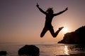 Happy young woman jumping on the beach at sunset Royalty Free Stock Photo