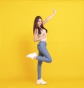 Happy  young woman  jumping and celebrating  isolated over yellow Royalty Free Stock Photo