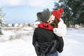 Happy young woman keeps hands in heart shape and kiss her boyfriend. Young loving couple in winter forest. Sunny day