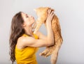 Happy young woman kissin and holding on the hands her red maine coon kitten and kissing. Closeup portrait Royalty Free Stock Photo