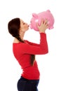 Happy young woman kissing a piggybank Royalty Free Stock Photo