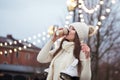 Happy young woman in knitted sweater and hat is going skating and drinks coffee