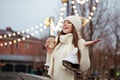 Happy young woman in knitted sweater and hat is going skating and drinks coffee