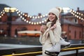 Happy young woman in knitted sweater and hat is going skating