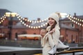 Happy young woman in knitted sweater and hat is going skating