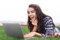 Happy young woman with laptop resting on green grass outdoors Royalty Free Stock Photo