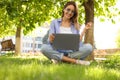 Happy young woman with laptop sitting on green grass in park Royalty Free Stock Photo