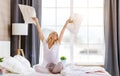 Happy young woman laughing and jumping on the bed in morning at home