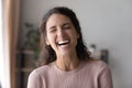 Happy young woman laughing standing alone at home