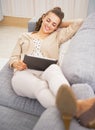 Happy young woman laying on divan and using tablet pc Royalty Free Stock Photo