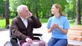 Happy young woman listening to music with old disabled man, supporting patient Royalty Free Stock Photo