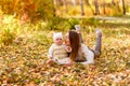 Happy young woman and little one-year-old girl lie on yellow leaves in autumn Royalty Free Stock Photo