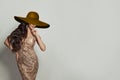 Happy young woman with long curly hair wearing gold dress and wide brown broad brim hat against white background Royalty Free Stock Photo