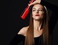 Happy young woman with long silky straight hair in black bodysuit holds holds red hair straightener at her head Royalty Free Stock Photo