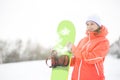 Happy young woman looking away while holding snowboard in snow Royalty Free Stock Photo