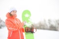 Happy young woman looking away while holding snowboard in snow Royalty Free Stock Photo