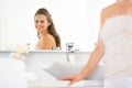 Happy young woman looking in mirror in bathroom Royalty Free Stock Photo