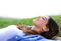 Happy young woman lying down on grass relaxing in a park in the city. Royalty Free Stock Photo