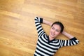 Happy young woman lying on wooden floor looking up Royalty Free Stock Photo