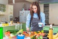 Happy young woman making cake smearing a layer with cream standing in kitchen Royalty Free Stock Photo