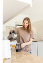 Happy young woman making coffee in kitchen - french press coffee. Caucasian female model in her twenties at home Royalty Free Stock Photo