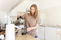 Happy young woman making coffee in kitchen - french press coffee. Caucasian female model in her twenties at home Royalty Free Stock Photo