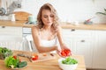 Happy young woman making a salad at the kitchen Royalty Free Stock Photo