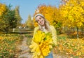 Happy young woman with maple bouguet is in autumn forest.