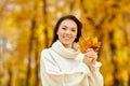 Happy young woman with maple leaves in autumn park