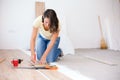 Happy young woman measuring and marking laminate floor tile for cutting Royalty Free Stock Photo