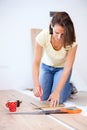 Happy young woman measuring and marking laminate floor tile installing laminate flooring in new apartment Royalty Free Stock Photo