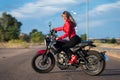 Happy young woman mounting on a red motorbike