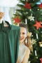 Happy young woman hiding behind festive green Christmas dresses