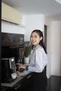 Happy young woman office worker making coffee from coffee machine in the office. Royalty Free Stock Photo