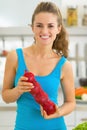 Happy young woman with onion in kitchen