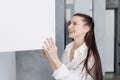 Happy young woman opening white cupboard with dishware