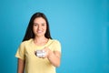 Happy young woman operating air conditioner with remote control on light blue background. Space for Royalty Free Stock Photo