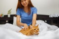 Happy young woman with orange cat lying in bed at home Royalty Free Stock Photo