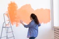 Dancing funny woman painting wall in her new apartment. Renovation, redecoration and repair concept. Royalty Free Stock Photo
