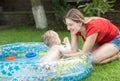 Happy young woman palying with her baby boy swimming in inflatable pool Royalty Free Stock Photo