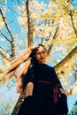 Happy young woman in park on sunny autumn day, smiling. Cheerful beautiful girl in black retro dress autumn fashion style Royalty Free Stock Photo