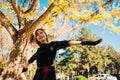 Happy young woman in park on sunny autumn day, smiling. Cheerful beautiful girl in black retro dress autumn fashion style Royalty Free Stock Photo