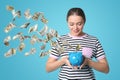 Happy young woman with piggy bank on color background. Money saving Royalty Free Stock Photo